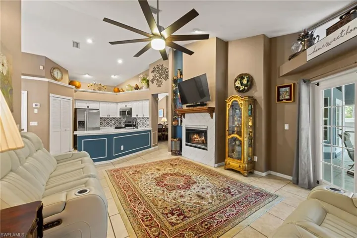 Living room featuring visible vents, high vaulted ceiling, a ceiling fan, light tile patterned flooring, and a tile fireplace
