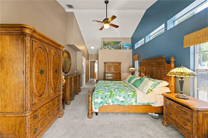 Bedroom with ceiling fan, visible vents, carpet floors, and high vaulted ceiling