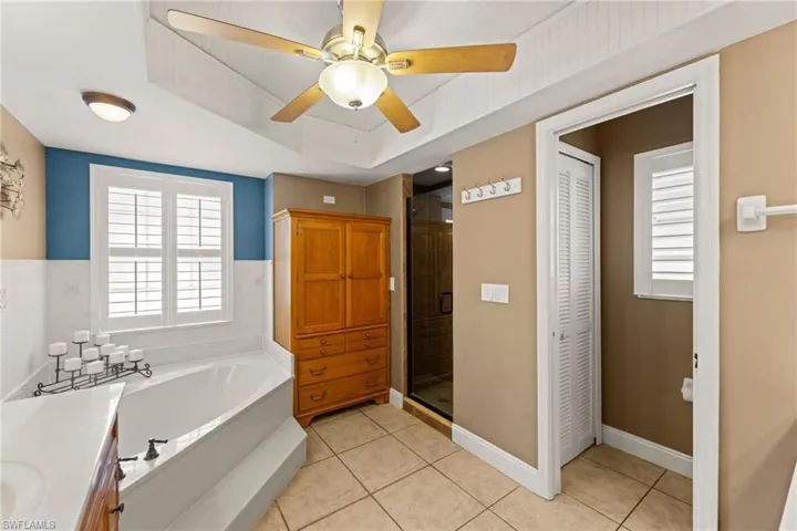 Bathroom featuring a garden tub, a ceiling fan, a closet, a shower stall, and tile patterned flooring