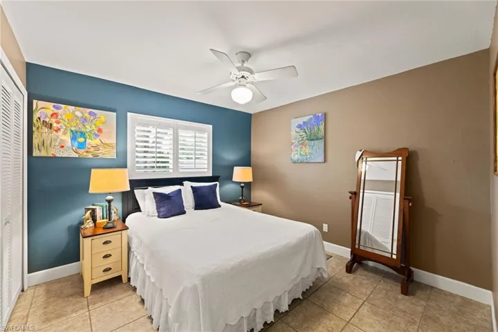 Bedroom with a closet, light tile patterned floors, a ceiling fan, and baseboards