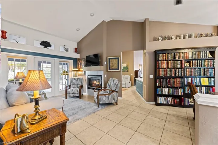 Living room featuring visible vents, high vaulted ceiling, light tile patterned flooring, and a tiled fireplace