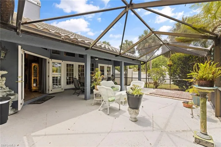 View of patio featuring glass enclosure, french doors, and a ceiling fan