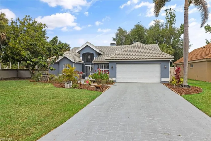 Single story home featuring driveway, an attached garage, stucco siding, a front lawn, and a tile roof