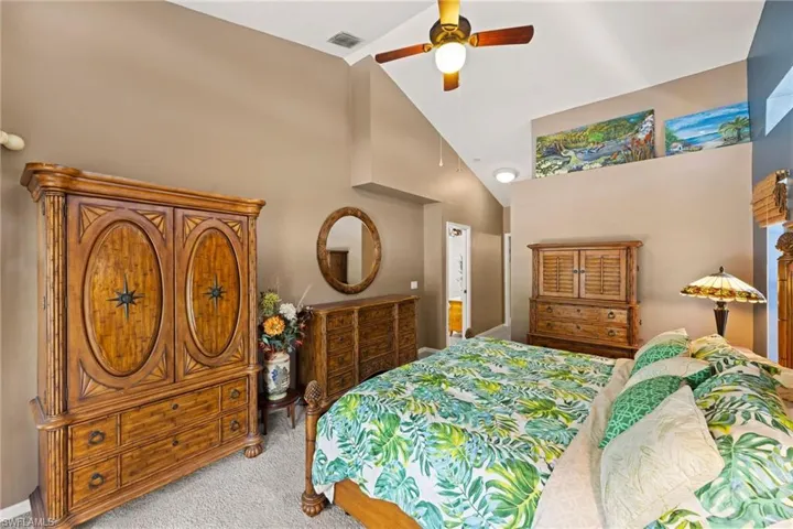 Bedroom featuring light carpet, visible vents, high vaulted ceiling, and ceiling fan