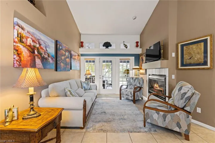 Tiled living room with baseboards, high vaulted ceiling, and a fireplace