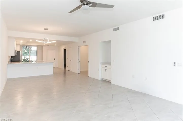 Unfurnished living room featuring ceiling fan with notable chandelier, light tile patterned flooring, and sink