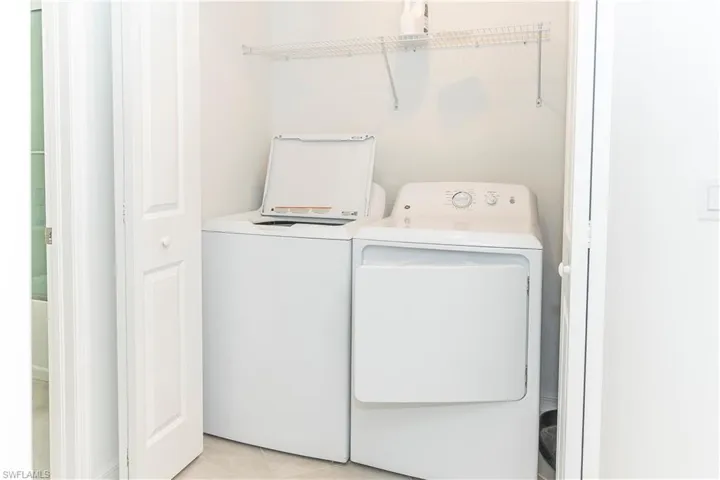 Laundry area with light tile patterned floors and washing machine and dryer