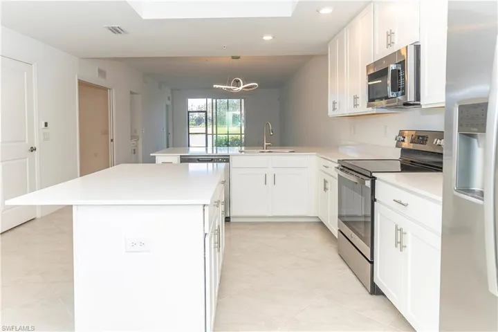 Kitchen featuring sink, stainless steel appliances, a kitchen island, kitchen peninsula, and white cabinets