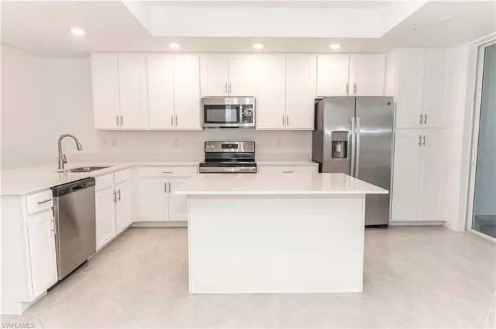 Kitchen with white cabinets, a center island, sink, and stainless steel appliances