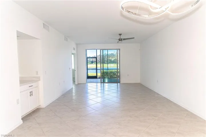 Empty room with ceiling fan and light tile patterned floors