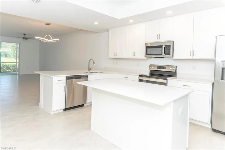 Kitchen featuring sink, stainless steel appliances, kitchen peninsula, decorative light fixtures, and a kitchen island