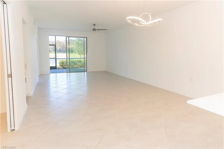 Tiled spare room featuring ceiling fan with notable chandelier