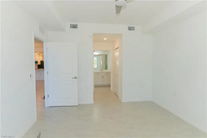 Empty room with ceiling fan and light tile patterned floors