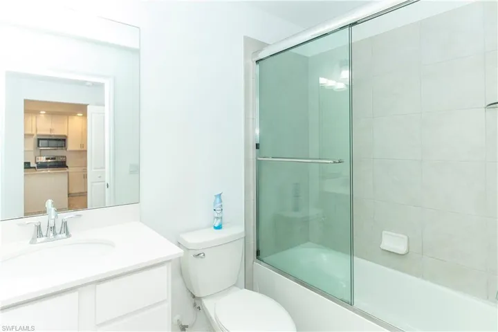 Full bathroom featuring shower / bath combination with glass door, vanity, and toilet