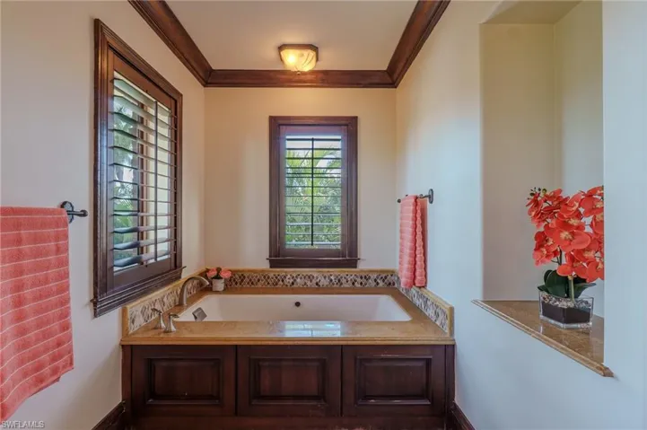 Bathroom with a garden tub and crown molding