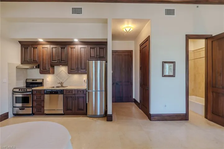 Kitchen featuring dark wood finish cabinets, stainless steel appliances, and tasteful backsplash