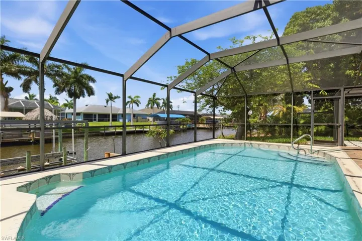 Screened outdoor pool area featuring a rectangular pool with an integrated step and handrail