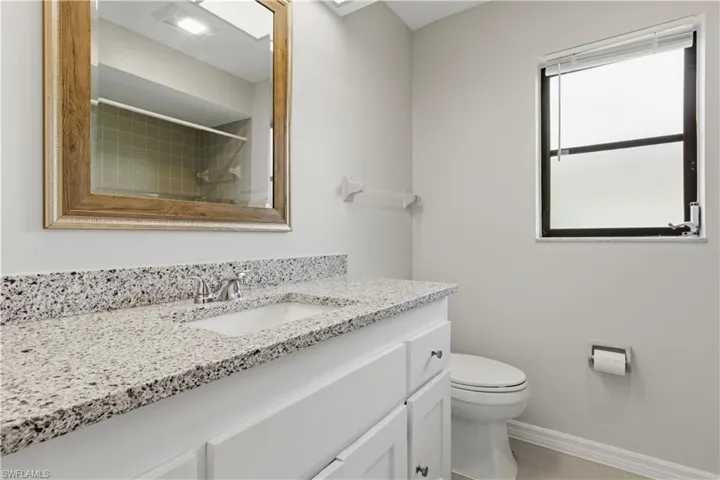 Bathroom vanity featuring a speckled countertop, undermount sink, and chrome faucet