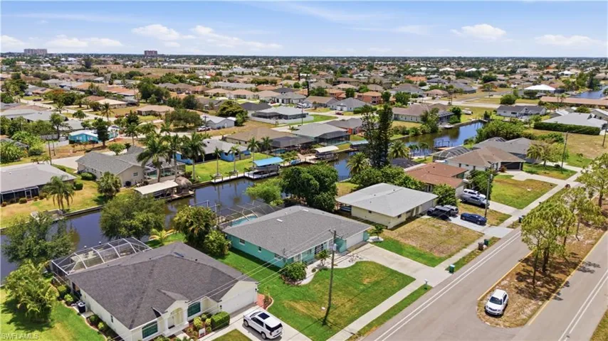 Expansive aerial view of a residential neighborhood featuring numerous single-story homes, many with private docks on canals