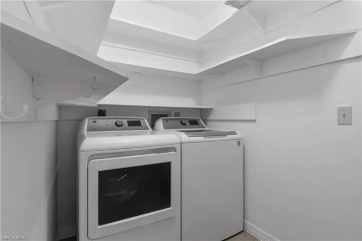 Laundry area featuring a washer and dryer, white walls, and integrated shelving