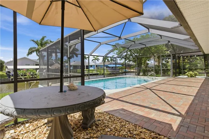 Screened lanai featuring a swimming pool, expansive brick paver patio, and water access