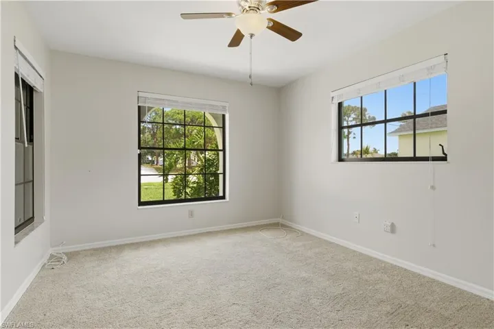Room featuring light-colored carpeting, multiple windows with white blinds, and a ceiling fan with integrated lighting