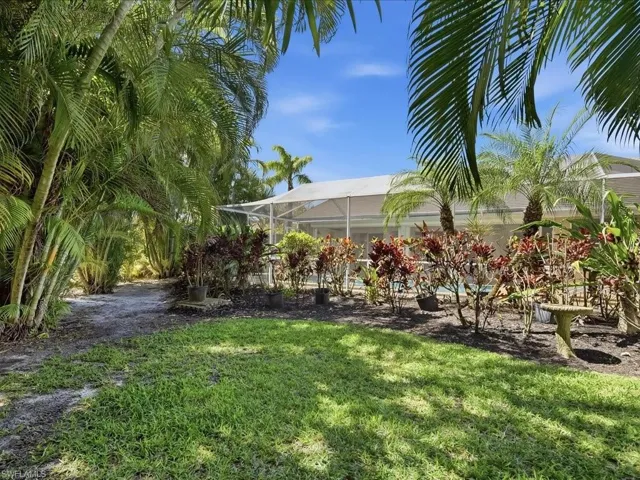 View of grassy yard with a sunroom and glass enclosure
