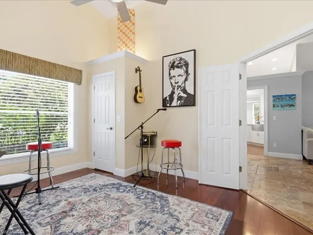 Living area with dark wood-type flooring, ceiling fan, and a high ceiling
