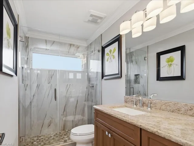 Full bathroom featuring crown molding, vanity, and a marble finish shower