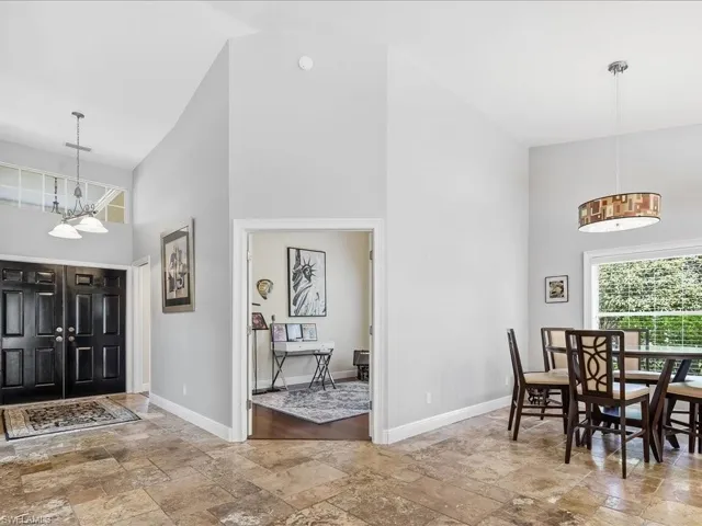 Foyer with hanging lights, stone tile floors, and vaulted ceiling