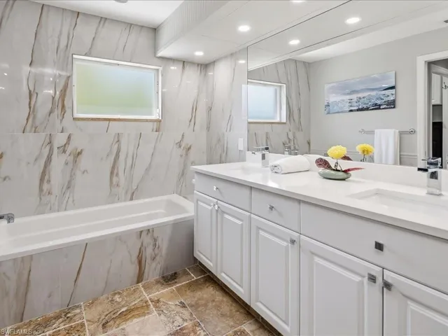 Bathroom with double vanity, stone tile floors, and recessed lighting