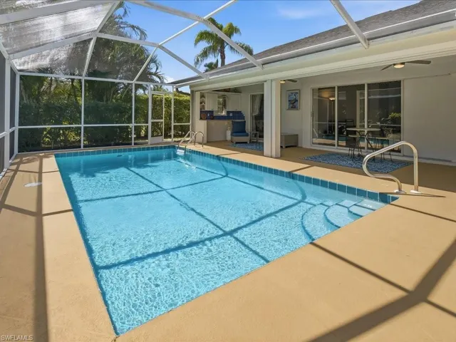 Outdoor pool with glass enclosure, a patio area, and a sunroom