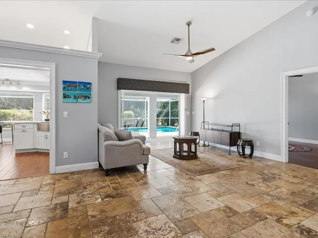 Living area featuring ceiling fan, a sunroom, and stone tile floors
