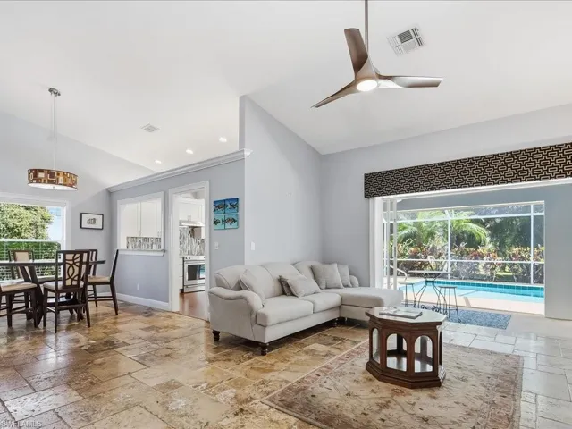 Living area featuring stone tile floors, a sunroom, vaulted ceiling, ceiling fan, and recessed lighting