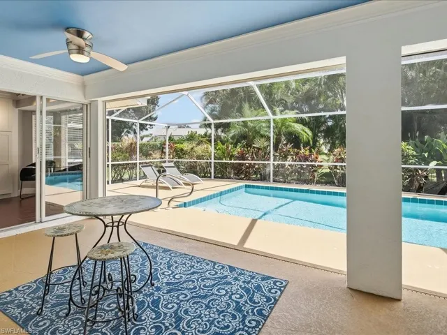 Outdoor pool featuring glass enclosure, a patio area, and a sunroom
