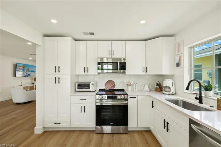 Kitchen featuring light hardwood / wood-style flooring, white cabinetry, sink, and stainless steel appliances