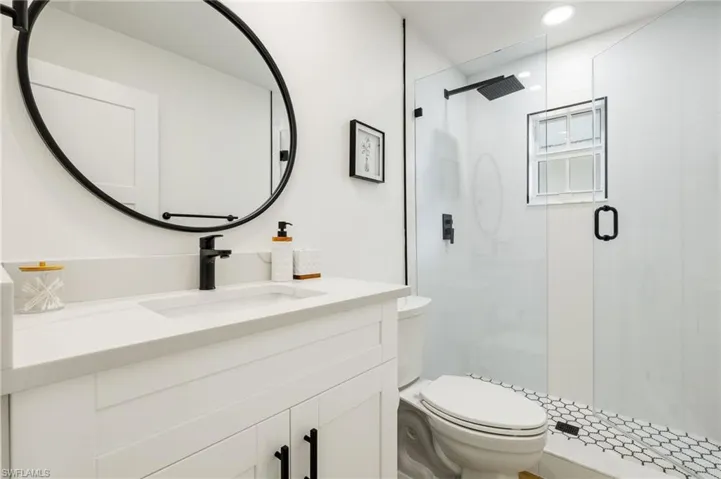 Bathroom featuring toilet, vanity, and a shower with shower door