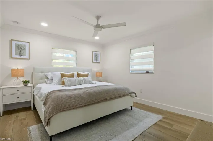 Bedroom with light hardwood / wood-style floors, ceiling fan, and ornamental molding