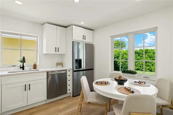 Kitchen with white cabinetry, appliances with stainless steel finishes, backsplash, light wood-type flooring, and sink