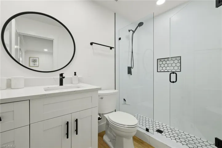 Bathroom featuring a shower with door, wood-type flooring, toilet, and vanity