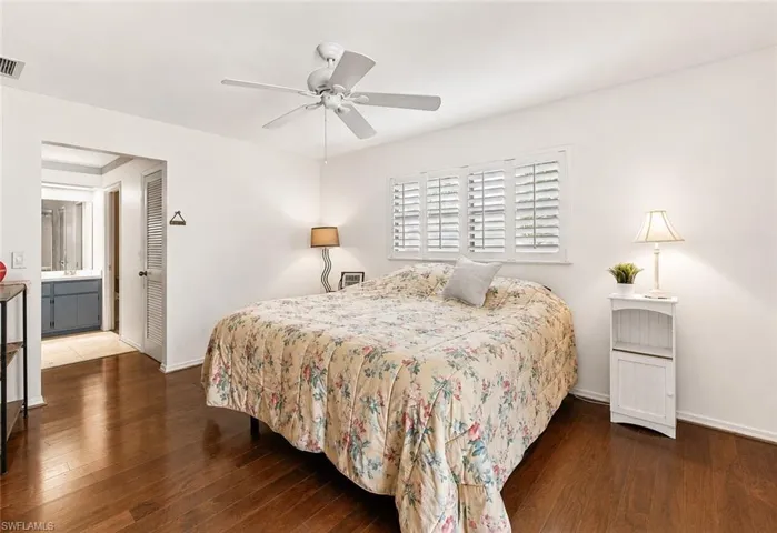Virtually Painted Walls. Hardwood flooring throughout, featuring a ceiling fan with integrated lighting, window with white plantation shutters, and a doorway opening to a bathroom with a vanity