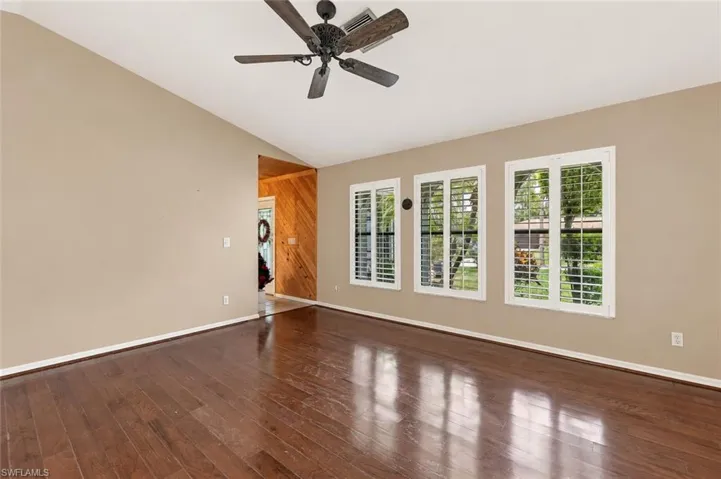 Virtual Wall Color - Vaulted ceiling with a ceiling fan, three windows with plantation shutters, wood-finish flooring, and a natural wood-paneled entrance