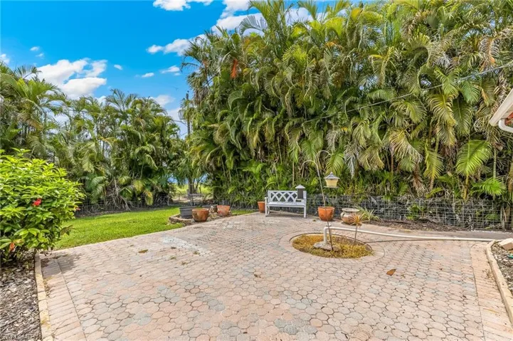 Paver patio area surrounded by lush tropical landscaping and a manicured lawn