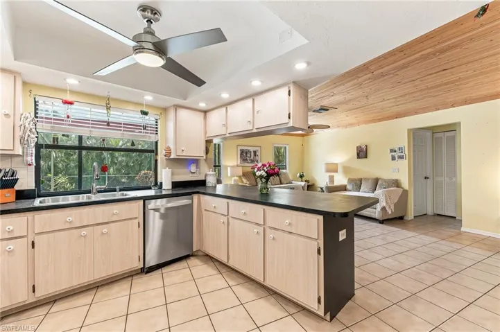 Kitchen featuring wood-finish cabinetry, stainless steel dishwasher, and dark countertops