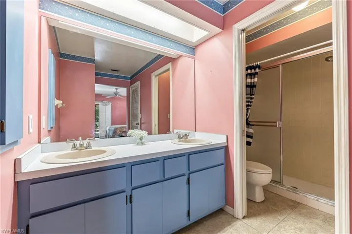 Bathroom featuring a double vanity with integrated sinks, a wide mirror, and blue cabinetry.