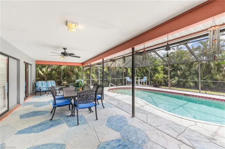 Screened-in patio with an in-ground swimming pool, featuring a ceiling fan, recessed lighting, and a textured concrete deck with blue accents