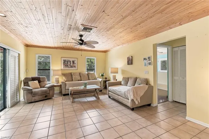 Living area featuring a wood-plank ceiling, light tile flooring, and a ceiling fan.