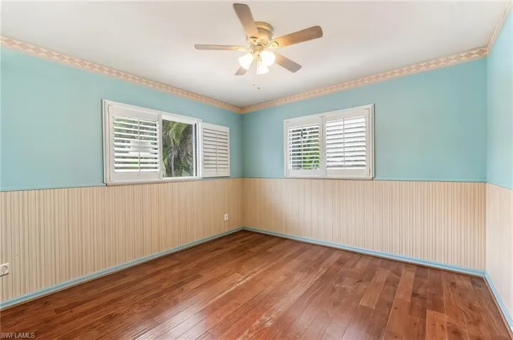 Wood flooring anchors this room, chair rail, plantation shutters complemented by a ceiling fan with integrated lighting
