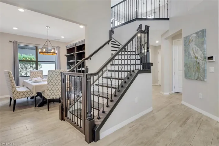 Stairway featuring baseboards, an inviting chandelier, recessed lighting, a high ceiling, and wood finished floors