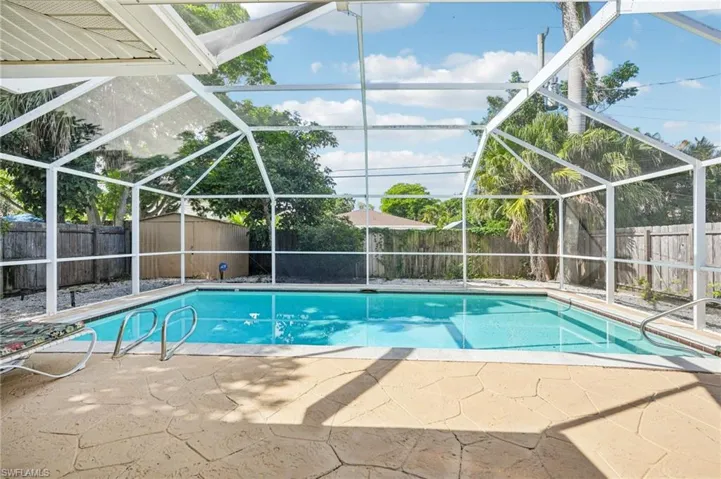 View of swimming pool featuring a fenced backyard, a sunroom, a lanai, and patio surround